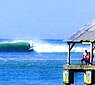 Man surfing famous Hanalei Bay while vacationers spectate from Hanalei Pier in the foreground